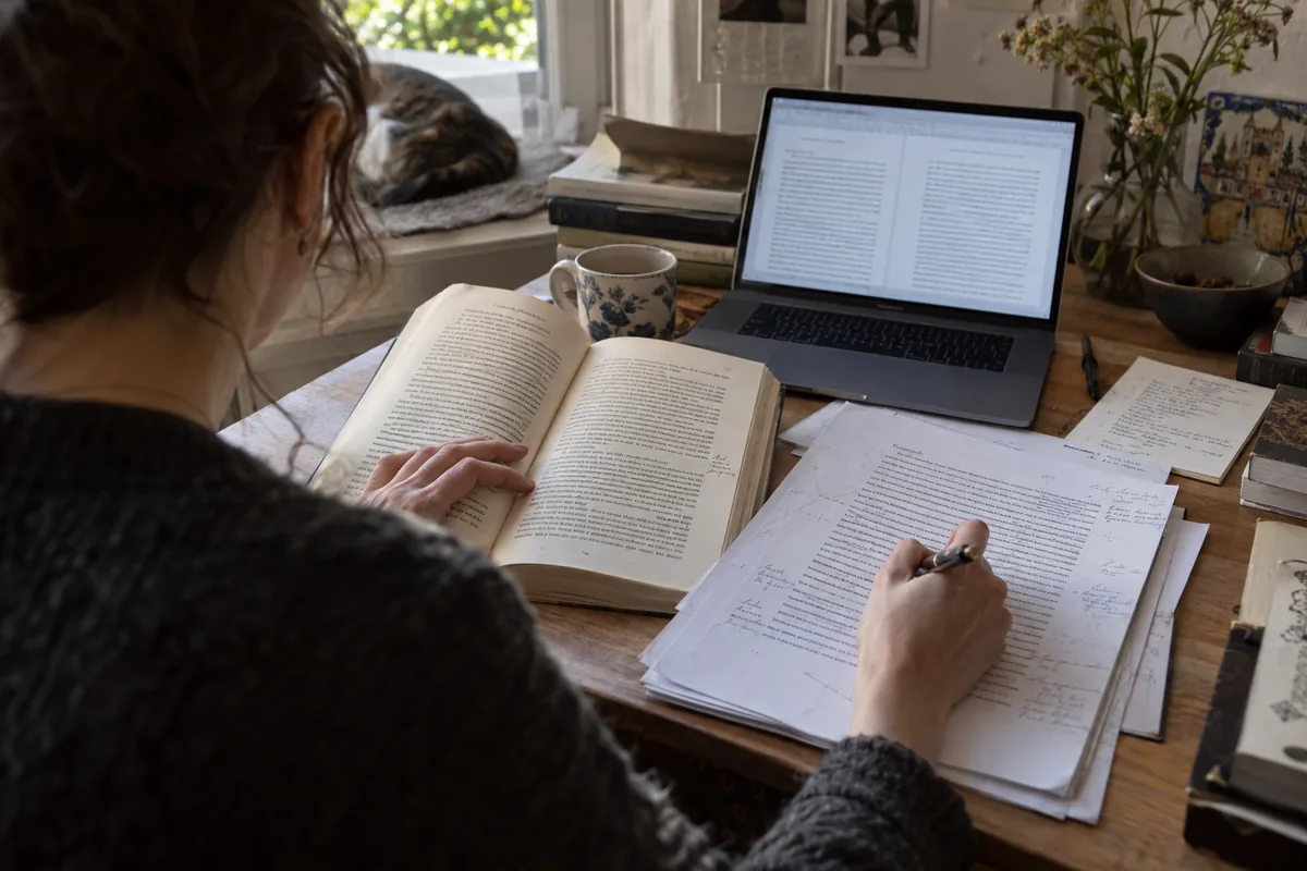 Traductrice compare un livre ouvert à un texte annoté sur son bureau